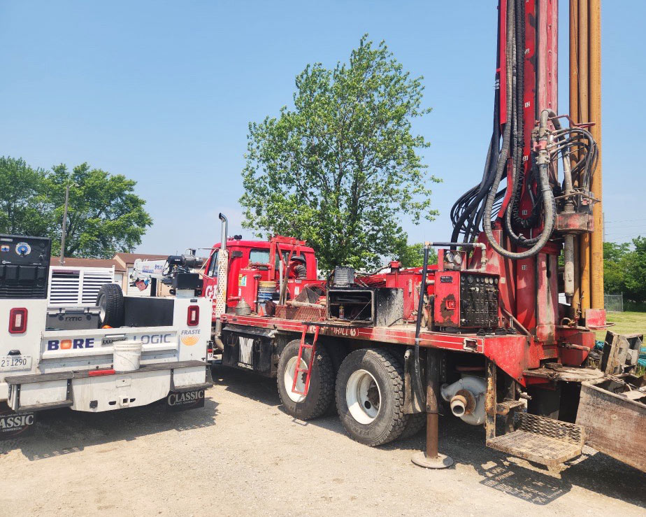 Bore Logic team servicing a red drill rig and field equipment for maintenance and calibration.