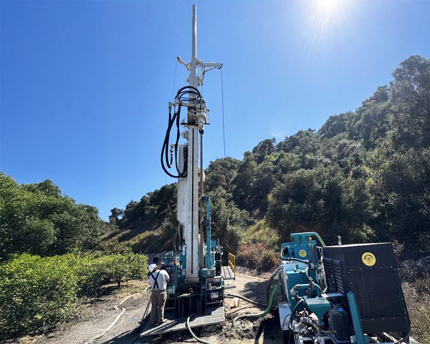 Field drilling training with Bore Logic crew operating hydraulic rig on rugged terrain.